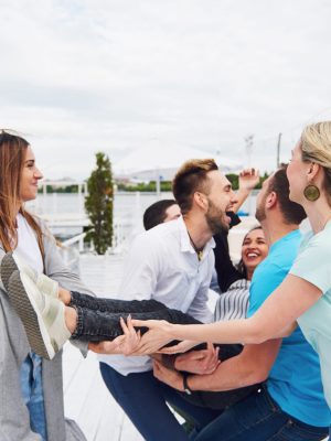 Group of happy friends at the beach, man tossing a happy woman. Group of happy friends at the beach, man tossing a happy woman